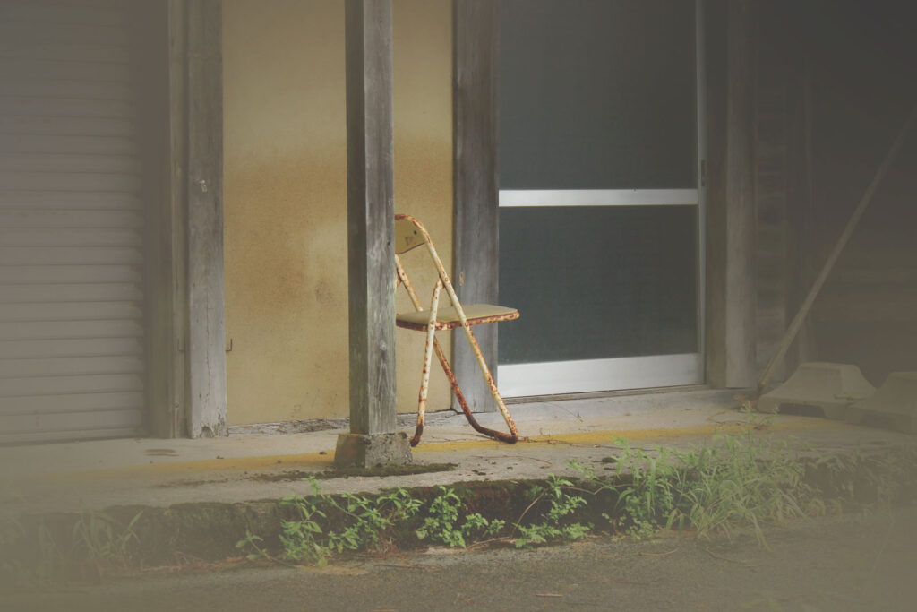 誰にも座られなくなった椅子が家の前に置かれている